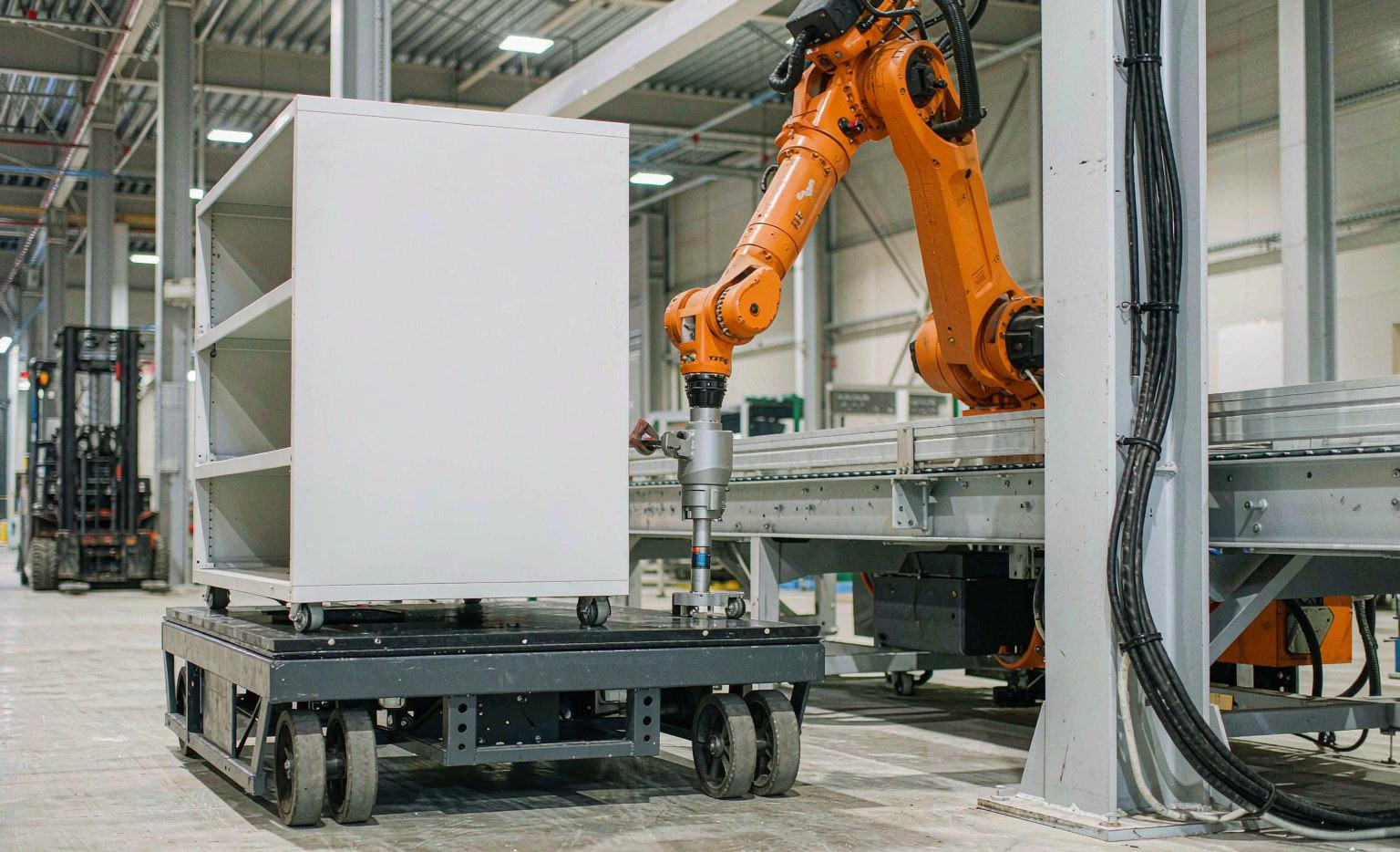 Autonomous mobile robot (AGV) and robotic arm handling loads in a warehouse