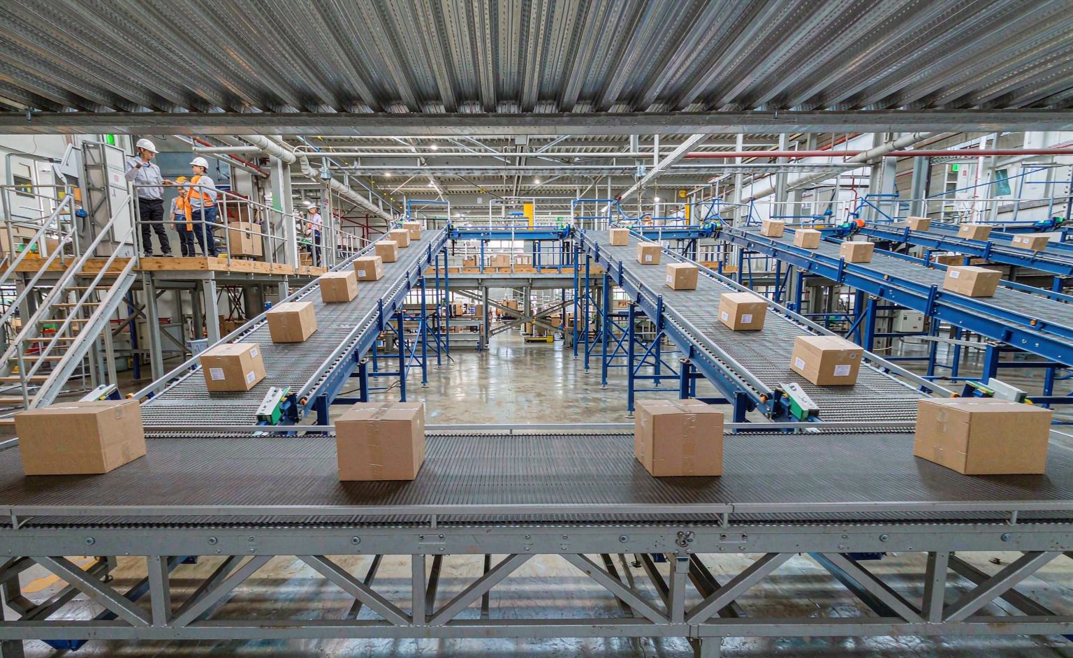 Narrow belt sorter carriers transporting cartons in an e-commerce fulfillment center