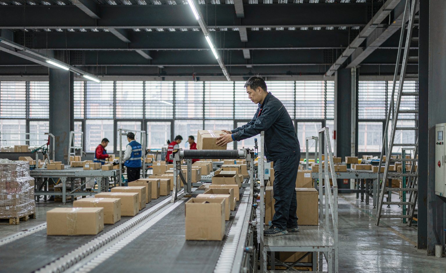 Operator placing parcels onto the induction section of a cross-belt conveyor sorter