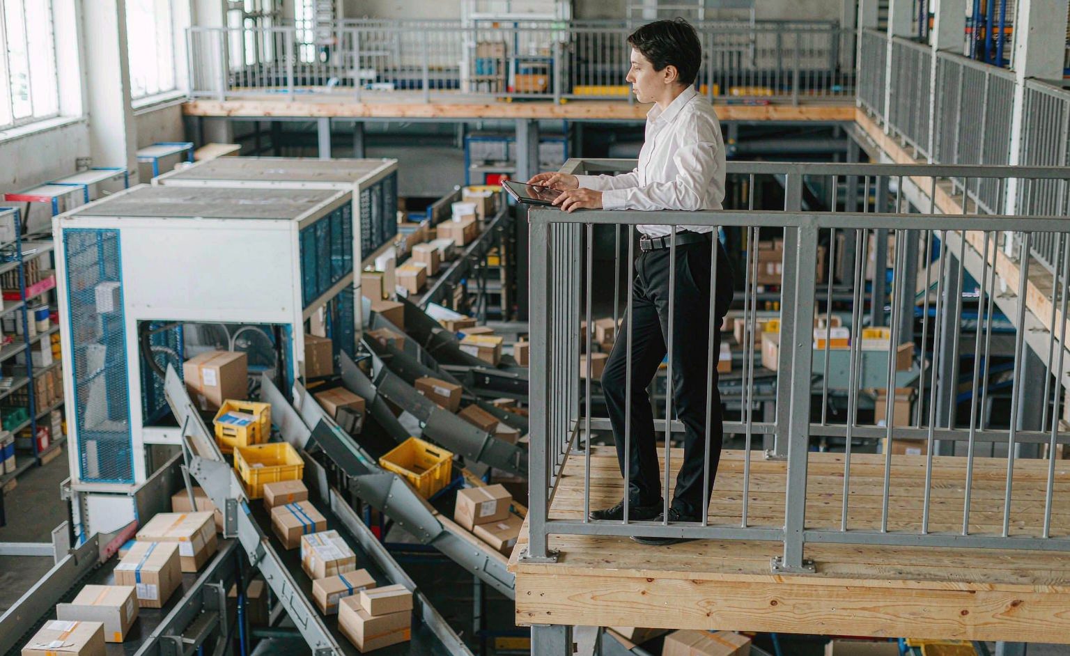 Manager with a tablet overlooking a busy parcel sortation line with chutes