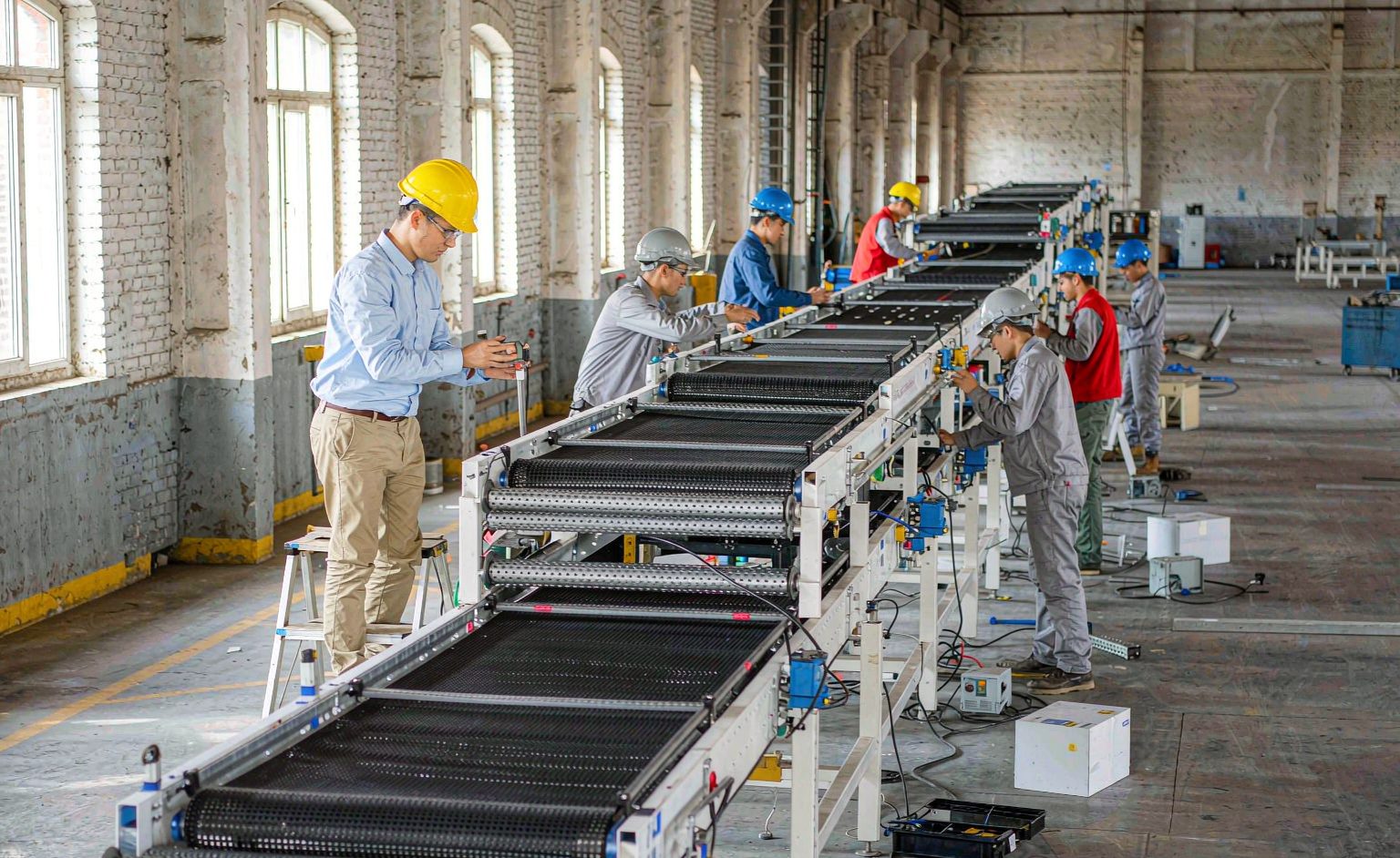 Engineers in safety helmets aligning conveyor segments during a sorter installation